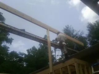 Carpenter setting a ridge beam over a new addition frame — Ice Dam Removal by Roofing Brothers in Greensboro