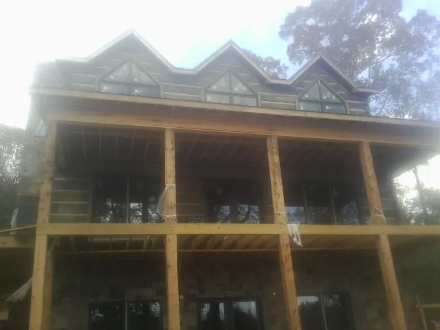 Dormers and porch framing on a large log home under construction — Roof Coating work by our crew in Greensboro