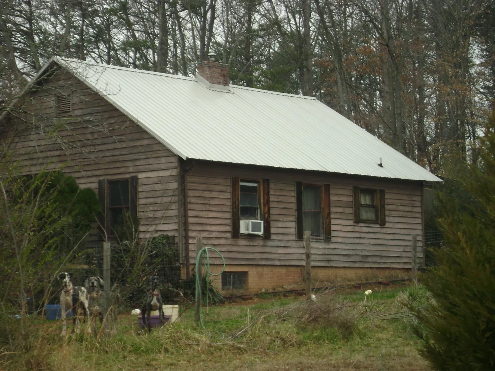 White metal roof on an old wood sided farmhouse, from a Asphalt Shingle Roof Repair job in Greensboro